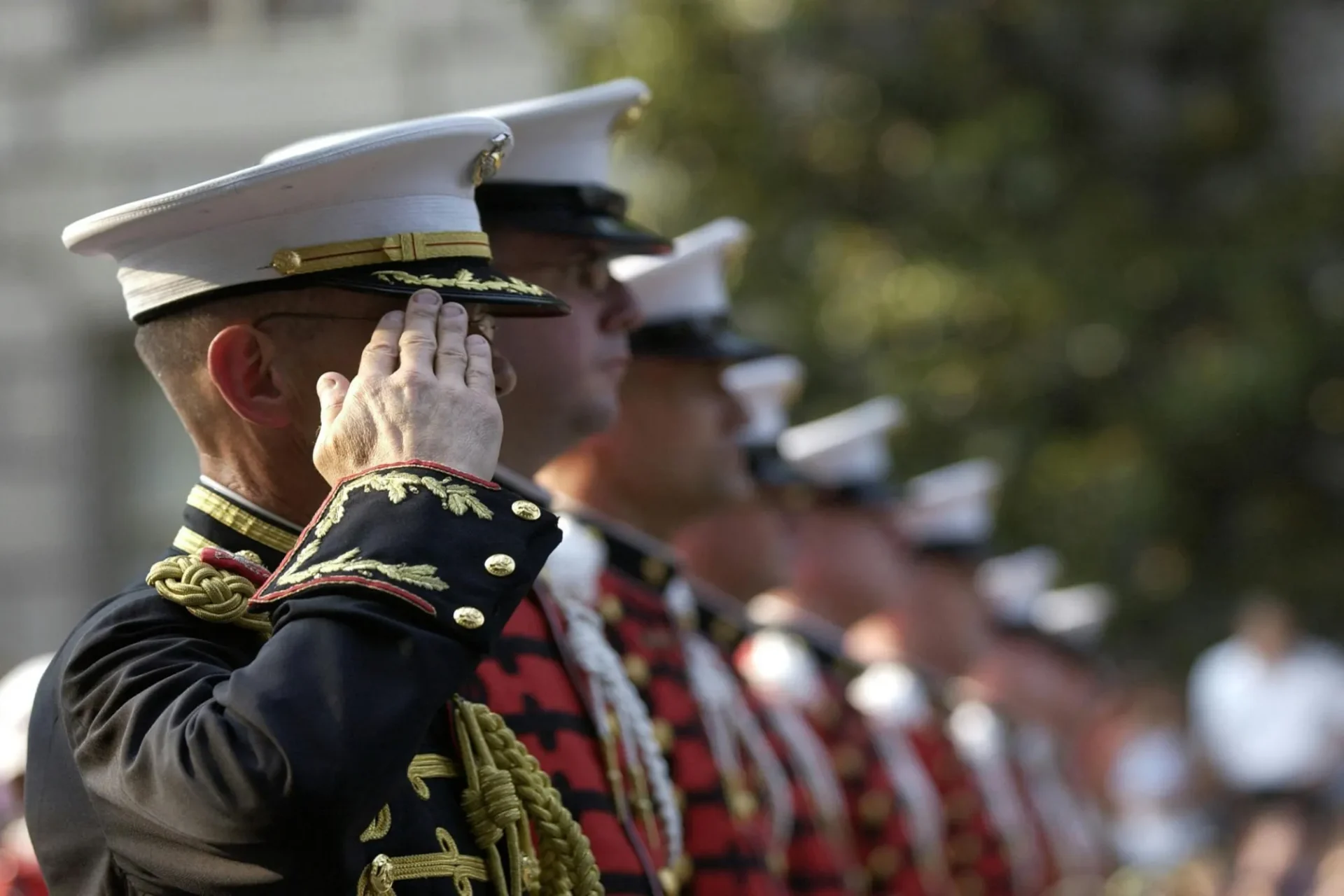 A line of military men saluting in uniform.