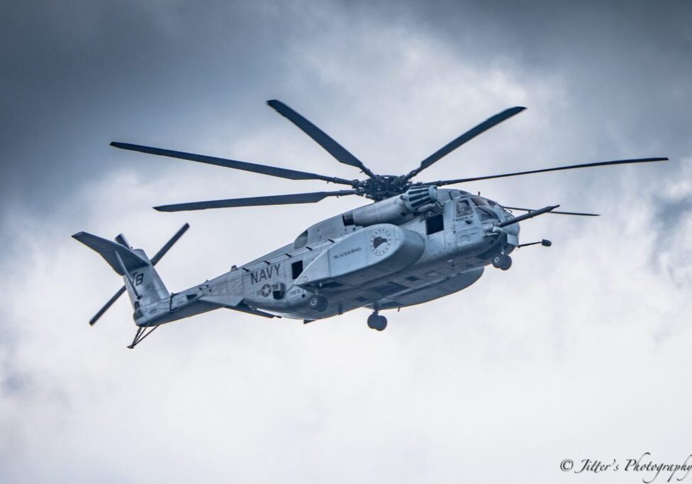 A helicopter flying in the sky under cloudy skies.