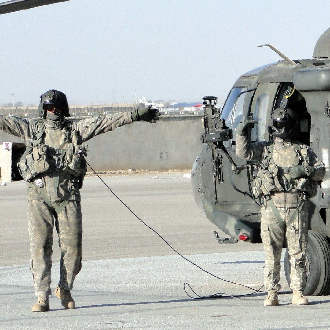 Two soldiers are standing next to a helicopter.